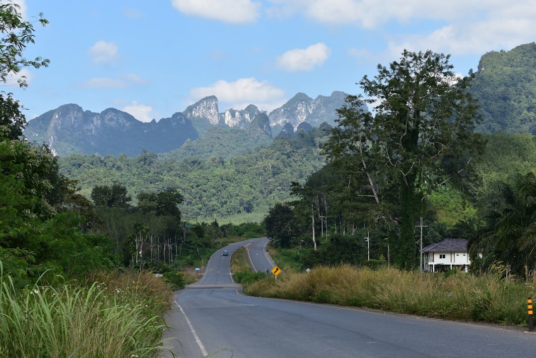 Winding mountain road through misty green hills in Northern Thailand with a car driving through curves